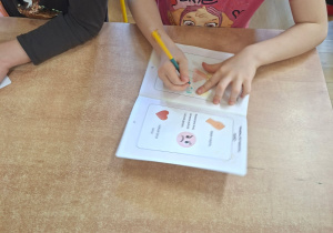 Na tym zdjęciu widać Marcelinkę T. wykonującą zadanie w kartach pracy.