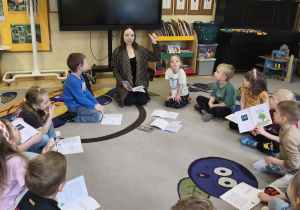 Na tym zdjęciu widać prowadzącą zajęcia oraz dzieci siedzące w kole podczas omawiania treści wysłuchanego opowiadania.