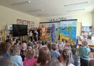 Zdjęcie przedstawia troje dzieci wraz z bohaterami: Tygryskiem i Kłapouchym na scenie oraz przedszkolaki oglądajace bajkę.