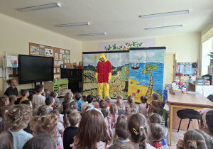Zdjęcie przedstawia Kubsia Puchatka na scenie i dzieci oglądające bajkę.