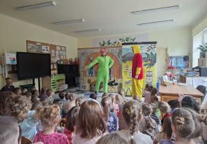 Zdjęcie przedstawia jedną ze scen teatrzyku i dzieci oglądające przedstawienie.