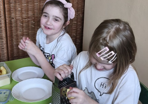 Zdjęcie przedstawia Marcelinę Ł. oraz Wandę z grupy IV ścierające na tarce produkty do sałatki jajecznej.