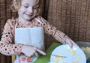 Na tym zdjęciu widać Oliwię z grupy III przekładajacą pokrojone jajko do talerza.