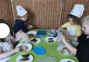 Zdjęcie przedstawia czworo dzieci z grupy III wykładających produkty potrzebne do przyrządzenia pasty z tuńczyka.