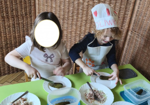 Na tym zdjęciu widać Oliwię z koleżanką z grupy III, które kroją ogórka kiszonego w kostkę.