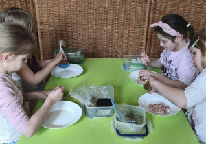 Zdjęcie przedstawia czworo dzieci z grupy IV, które wykładają tuńczyka z puszki na talerz.