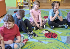 Zdjęcie przedstawia kilkoro dzieci siedzącyh na dywanie podczas warsztatów.