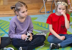 Zdjęcie przedstawia Zuzię M. i Julka siedzących na dywanie podczas zajęć.