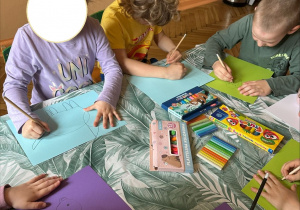 Na tym zdjęciu widać troje dzieci z grupy III wykonujących pracę pt. "Moje wymarzone zwierzątko".