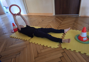 Zdjęcie przedstawia Filipa z grupy IV przekładająceo krążki z pachołka na pachołek w lężeniu tyłem.