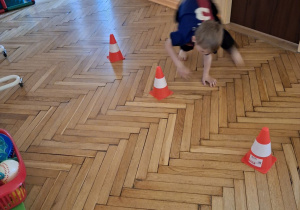 Na tym zdjęciu widać Wojtka z grupy III wykonujacego slalom na czworakach między pachołkami.