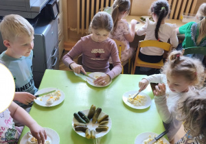 Zdjęcie przedstawia uczestników zajęć krojących jajka na drobne kawałki.