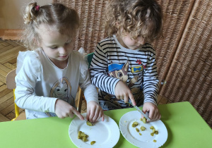 Zdjęcie przedstawia Oliwię i Mikołaja z grupy III, którzy kroją ogórki na drobne kawałki.