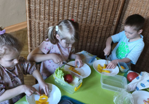 Na tym zdjęciu widać Oliwię z grupy III oraz Wandę i Stasia W. z grupy IV, którzy kroją brzoskwinie na drobne kawałki.