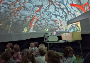Zdjęcie przedstawia dzieci z grupy I oglądające film "Krecik w Kosmosie" wyświetlany w kopule.