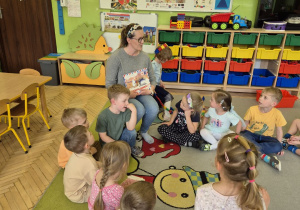 Na tym zdjęciu widać mamę Adasia oraz dzieci siedzące na dywanie.