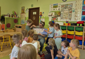 Na tym zdjęciu widać mamę Adasia, która pokazuje dzieciom ilustracje w książeczce.