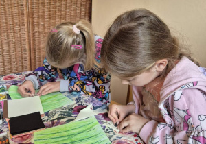 Zdjęcie przedstawia dwie dziewczynki z grupy IV podczas wykonywania pracy "Pies i kot".