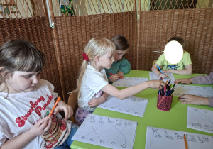Na tym zdjęciu widać czworo dzieci z grupy IV wykonujące kartę pracy "Emocje".