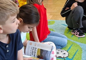 Zdjęcie przedstawia Filipa, Julka i Klarę P. oraz Olę L., które ogląda ilustracje w jednej z książek.