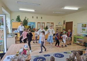 Zdjęcie przedstawia dzieci tańczące poloneza pod okiem tancerek.