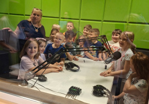 Zdjęcie przedstawia dzieci wraz z nauczycielką w sali radiowej.