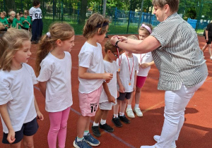 Na tym zdjęciu widać moment wręczania medali dzieciom przez panią dyrektor.