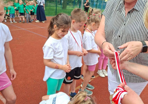 Na tym zdjęciu widać moment wręczania medali dzieciom przez panią dyrektor.