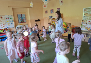 Na tym zdjęciu widać mamę Mikołaja oraz dzieci podczas zabawy ruchowej przy muzyce.