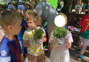 Zdjęcie przedstawia troje dzieci z grupy III z kwiatkami do sadzenia.