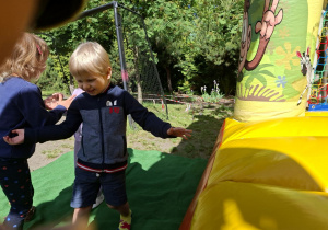 Zdjęcie przedstawia Henia D. z grupy I przed zjeżdżalnią.