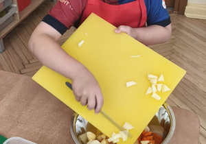 Na tym zdjęciu widać Adasia W. z grupy IV, który zsypuje pokrojone warzywa do miski.