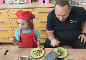 Na tym zdjęciu widać Mikołaja z grupy III z tatą podczas degustacji sałatki owocowej.