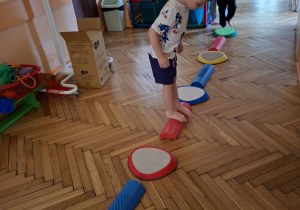 Na tym zdjęciu widać Maksymiliana, Kubę S. i Adama M. z grupy II wykonujących ćwiczenia z wykorzystaniem kamieni rzecznych i ścieżki sensorycznej.