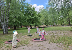 Na tym zdjęciu widać kilka dziewczynek bawiących się na trampolinach.