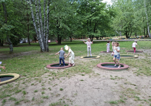 Na tym zdjęciu widać kilkoro dzieci bawiących się na trampolinach..