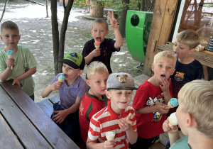 Zdjęcie przedstawia ośmiu chłpopców jedzących lody.