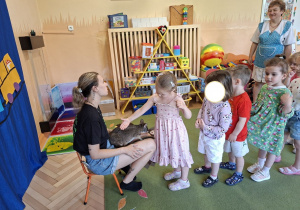 Zdjecie przedstawia dzieci korzystające z możliwości pogłaskania kangurka.