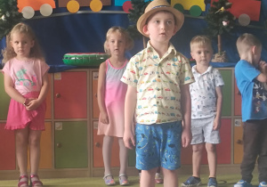 Zdjęcie przedstawia jednego z chłopców recytującego wierszyk oraz kilkoro innych dzieci.
