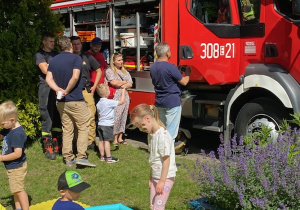 Zdjęcie przedstawia dzieci i rodziców przy wozie strażackim.