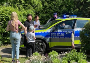 Na tym zdjęciu widać jedną z mam z dzieckiem przy radiowozie policyjnym.
