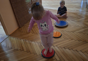 Na tym zdjęciu widać Natalkę z grupy I, która wykonuje ćwiczenia stóp z wykorzystaniem krążków masujących.