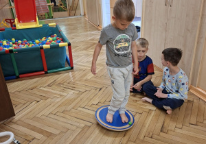 Na tym zdjęciu widać Tymka z grupy III podczas wykonywania ćwiczeń równoważnych z wykorzystaniem kół do balansowania.