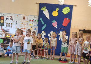 Na tym zdjęciu widać Jagodę L. i Dominika S. z grupy II recytujących wierszyk oraz inne dzieci występujące w przedstawieniu stojące z tyłu.
