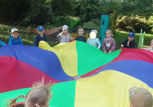 Zdjęcie przedstawia dzieci z grupy III podczas zabaw z chustą animacyjną.