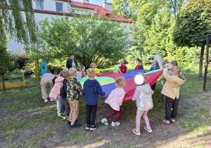 Zdjęcie przedstawia dzieci z grupy IV podczas zabaw z chustą animacyjną.