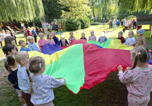 Zdjęcie przedstawia dzieci z grupy II podczas zabaw z chustą animacyjną.