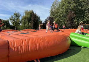 Zdjęcie przedstawia dzieci bawiące się na "dyniowych" dmuchańcach.