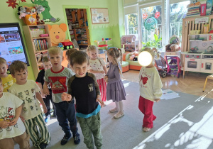 Zdjęcie przedstawia dzieci podczas zabawy ruchowej połączonej z odtwarzaniem mimiką różnych stanów emocjonalnych.