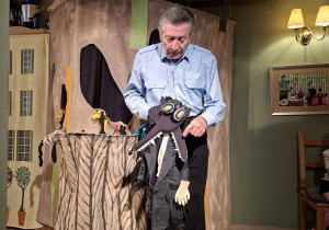 Zdjęcie przedstawia aktora prezentującego marionetkę - wilka.